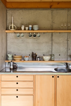 Kitchen of the Dogbox. A poured insitu concrete wall on the lower floor works both as thermal mass and as a retaining wall to the steep bank behind. 