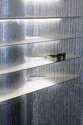 The bespoke display objects include blade-like shelves of stainless steel that cut through the curving walls.