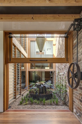 The internal-external courtyard forms the nucleus of the home. A counterweighted door system is aided by a bespoke antique farm wheel.