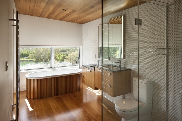 Te Hīnaki House. This timeless bathroom draws on the timber theme of the rest of the house, with the addition of white hexagonal tiling.
