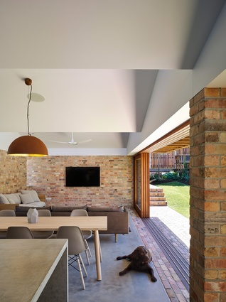 The exterior brick paving is flush with the interior’s concrete floors, making the transition between indoor and outdoor spaces ambiguous.