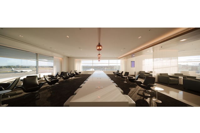 This business space in the Koru Lounge in Sydney airport features a communal table with integrated power and data ports. The signature violet color is used for the lights.