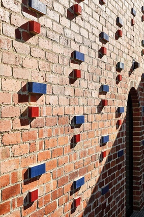 The red and blue brick accents provide a sense of playfulness and reduces the otherwise imposing nature of the brick wall.