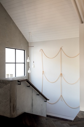 An artwork by Peter Robinson graces the stairwell leading up to the bedroom spaces.  