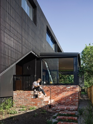 The cantilevered living area, which offers access to the garden from both ends, is wrapped in red brick.


