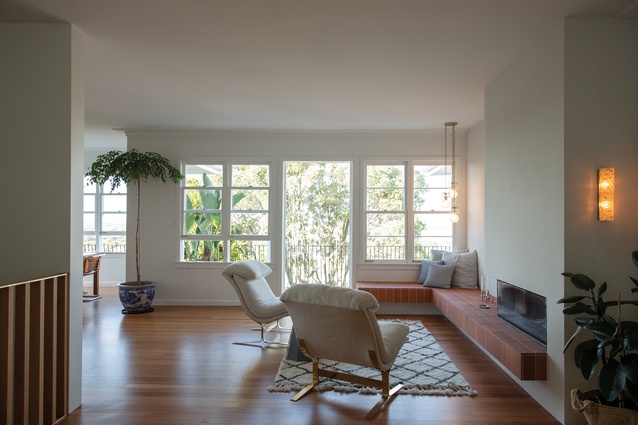 Architect Raukura Turei removed walls from the body of the home to create view shafts from the back garden to the front. In the main living area, chairs from Mid Century Swag and a rug from Freedom Furniture define a zone in front of the fireplace.