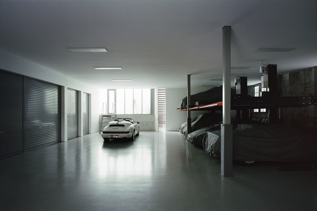 A workshop area houses a collection of Porsche sports cars.