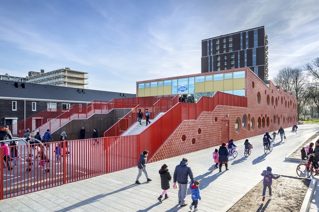 IKC Zeven Zeeën, Amsterdam. The entrance of the superstructure is via a large, bright outdoor staircase, and the red concrete facade and round windows add a playful element.