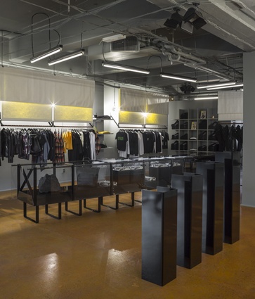 The canvas textile used for the hanging racks creates a contrast against the black industrial typology of the store.