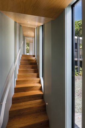 The corridor from the living spaces leads up a staircase to one of the bedrooms and features views over the internal courtyard to the right.