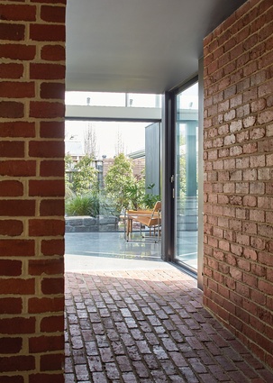 A heavily textured brick “tunnel” connects old and new; entering the bright new space from here makes for a grand reveal.