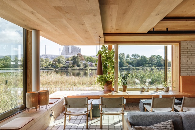 Timber and glass feature prominently throughout Noma’s interiors. Here, a room overlooks the site's grasslands and lake towards BIG's 2022 World Architecture Festival award-winning Copenhill/Amager Bakke project.