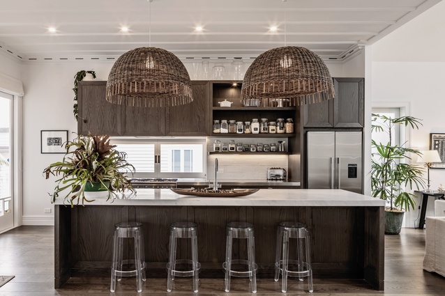 Plantation-style contrast between dark and light is encapsulated in the kitchen, designed by Robyn Labb. Featured in the space are Croco Rattan pendants from ECC and Kartell Ghost bar stools.