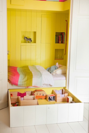 Bedstead made from old doors and shutters with hidden compartments for storage.  