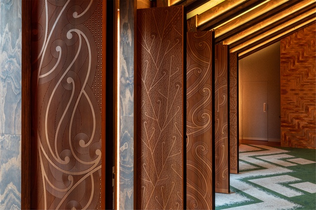 A detail of the finely carved totara poupou inside Te Rau Karamu wharenui. Eight of these poupou become doorways opening out to Nga Kuratinitini o Te Ao courtyard.