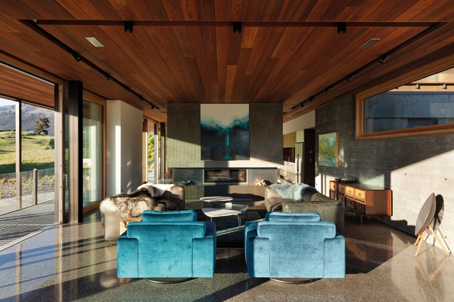 Twin blue-velvet armchairs create a colourful centrepiece in the living room. The ceiling is clad in richly toned Western red cedar from Herman Pacific.