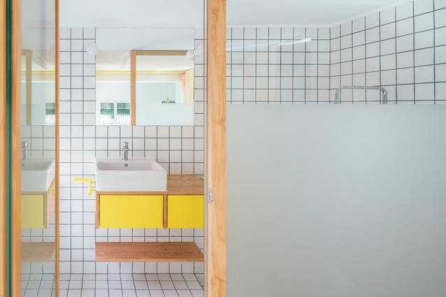 Coloured grout against white tiles is what gives this bathroom in a small apartment in Madrid by Elii architects its distinct aesthetic.