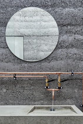 Charcoal rammed-earth walls in the bathroom have a monolithic feel and strong contextual relationship to the site. 
