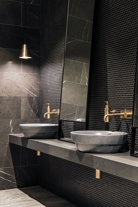 The public bathrooms feature dark, subtle textures and brass accessories.