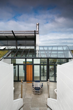 A sheltered courtyard space is created between the submerged side and the pavilion.