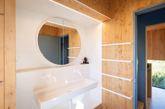 The main bathroom's all-white fittings and warm-wood wall lining gives it a fresh, inviting feel.