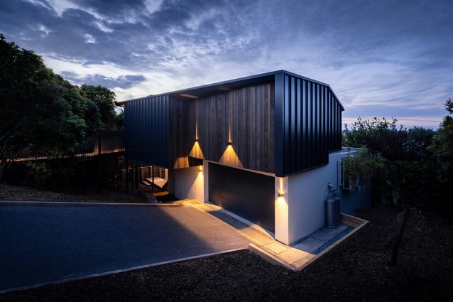 The house is primarily clad with a metal tray profile, with softer, vertical timber cladding to the entrance and northern outdoor living area.
