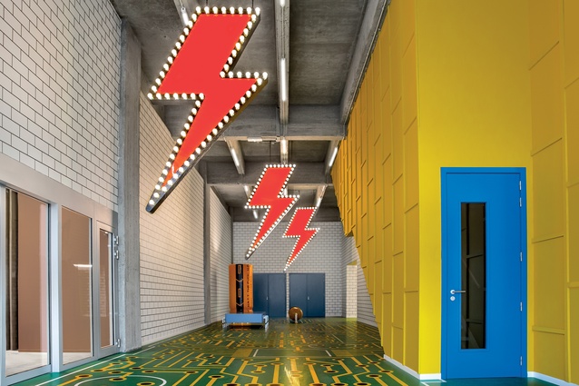 The perspective of the long lobby is exaggerated by the green and gold microchip floor and the Bowie-esque lightning bolts hung from the ceiling.