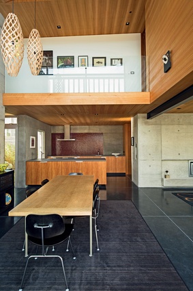 A house of shifting volumes and demarcated spaces, the double-height dining area affords a glimpse of the upper level.