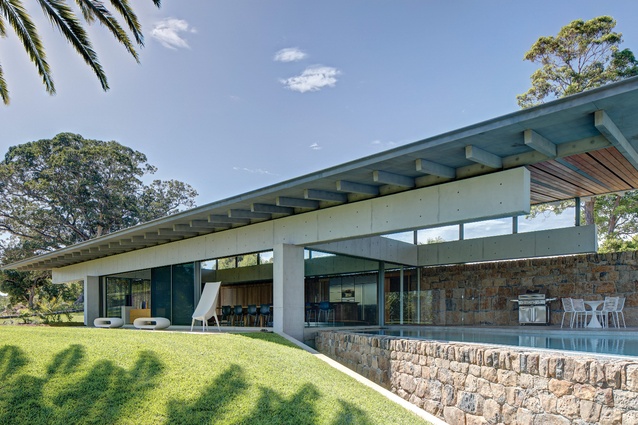A wall of local stone, broken with blackbutt in shaded areas, acts as a spine, stitching together the house and landscape as one.