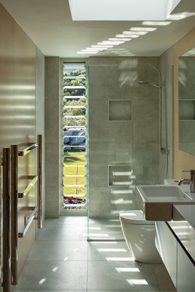 Oversized bathroom tiles tie in with the concrete floors throughout the house.