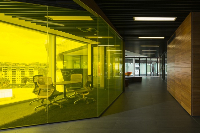 A yellow-tinted-glass meeting room casts reflective light over the entrance foyer. 