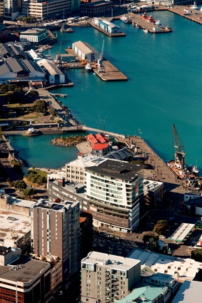An aerial view shows the building’s context near Taranaki Wharf and Te Wharewaka.