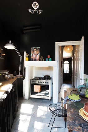 In the kitchen, the walls and ceiling are painted in matte black. Appliances are hidden behind black curtains. The hallway is the only space painted white. 