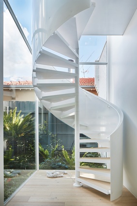 A glass-enclosed spiral stair forms the heart of the plan from which the main rooms unfurl.