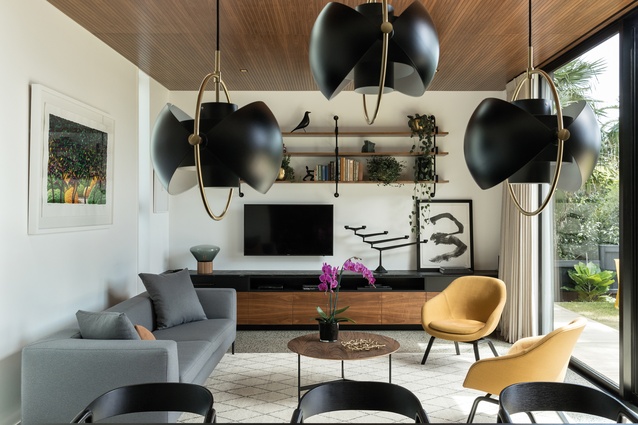 The double-height, main living room is full of walnut accents, such as the <a 
href="https://simonjames.co.nz/"style="color:#3386FF"target="_blank"><u>Simon James</u></a> coffee table. There are also foliage-inspired artworks, such as the Karl Maughan piece (pictured left), and amber-coloured armchairs from <a 
href="https://cultdesign.co.nz/shop/about-a-lounge-aal82-aal92"style="color:#3386FF"target="_blank"><u>Cult</u></a>. The amber colour is a nod to the owner/designer’s ancestry.
