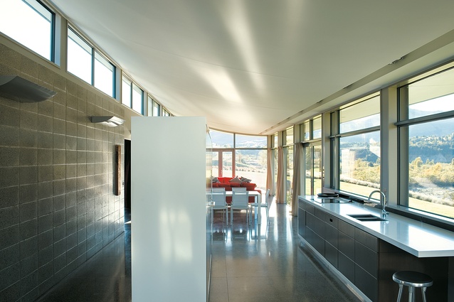 The heavy and thermally efficient concrete wall and floor contrast with the lightweight arcing roof. 