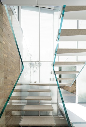 The uniquely sculptural form of the toughened glass stair has become a focal point in the space.