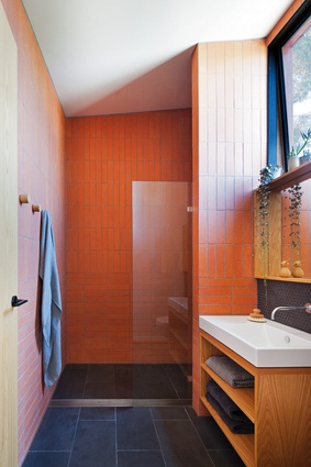 The red brick of the exterior and hallway are referenced in the ensuite’s terracotta tiles, which lend the space a tactile, earthy quality.