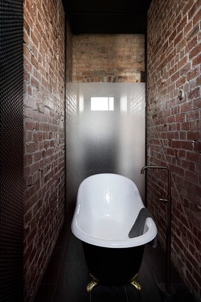 On the ground floor, another bathtub occupies a dramatic space compressed between four-metre-high brick walls.