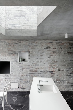 Recycled brick frames a generous light well that connects the kitchen to the first-floor bedroom wing.
