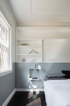 The bedroom features wood-panelled joinery in a warm blue-grey, referencing the panelling in the living area.
