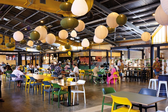 Interior of the market hall shows the simple shell enlivened with services, tasty food outlets and afternoon daylight – the antithesis of a standard mall.
