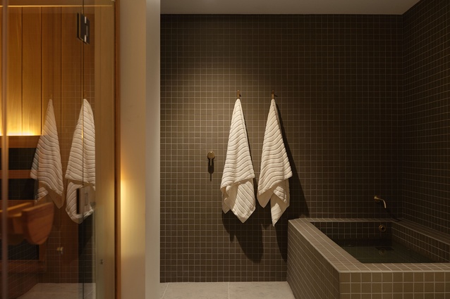 Imported dark green mosaic tiles bring mood and theatre, set against natural bluestone floors and paired with brass fixtures and fittings.