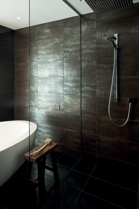 Lava Black polished metallic bronze tiles lend a calm sophisticated essence to the bathroom. 