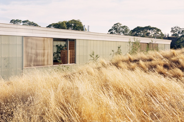 Sitting low among a series of landscaped berms, the home presents as an industrial shed.