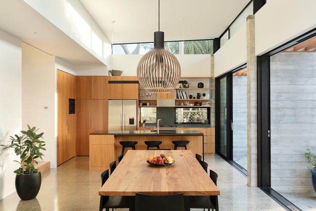 The earthy palette of the kitchen and dining space is offset by extensive glazing.