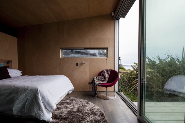 The master bedroom has views of Kapiti Island and a red BoConcept armchair. 