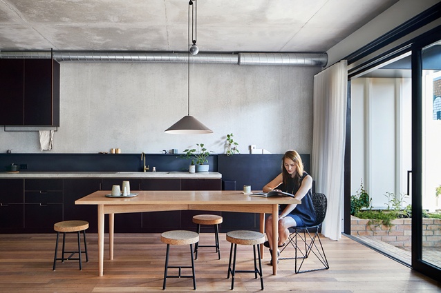 The kitchen cabinetry is clad in black film face plywood and the benchtops are concrete, poured in situ.