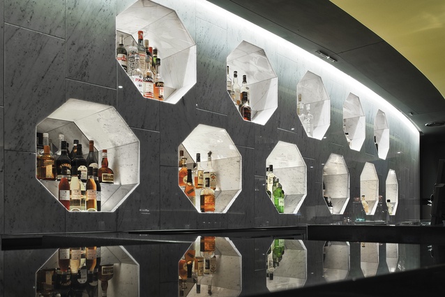 A handmade honeycomb-shaped tile with a rich glaze ties with the form of the octagonal niches behind the bar.
