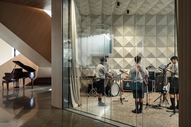 The orchestra and rock rooms face the foyer through acoustic glazing, allowing multiple musical practice events to coincide, including playing the baby grand under the stairway.